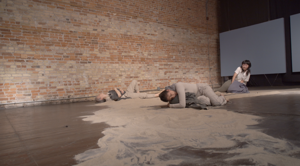 Image: Maria Plotnikova, Sofía Gabriel, and Chia Chun Huang shown holding the prop garments near or on their chest's in various positions during the John David Mooney Performance of Territory and People. Image by Mallory Qiu.